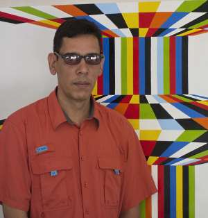 Antonio Paz in front of one of his  paintings